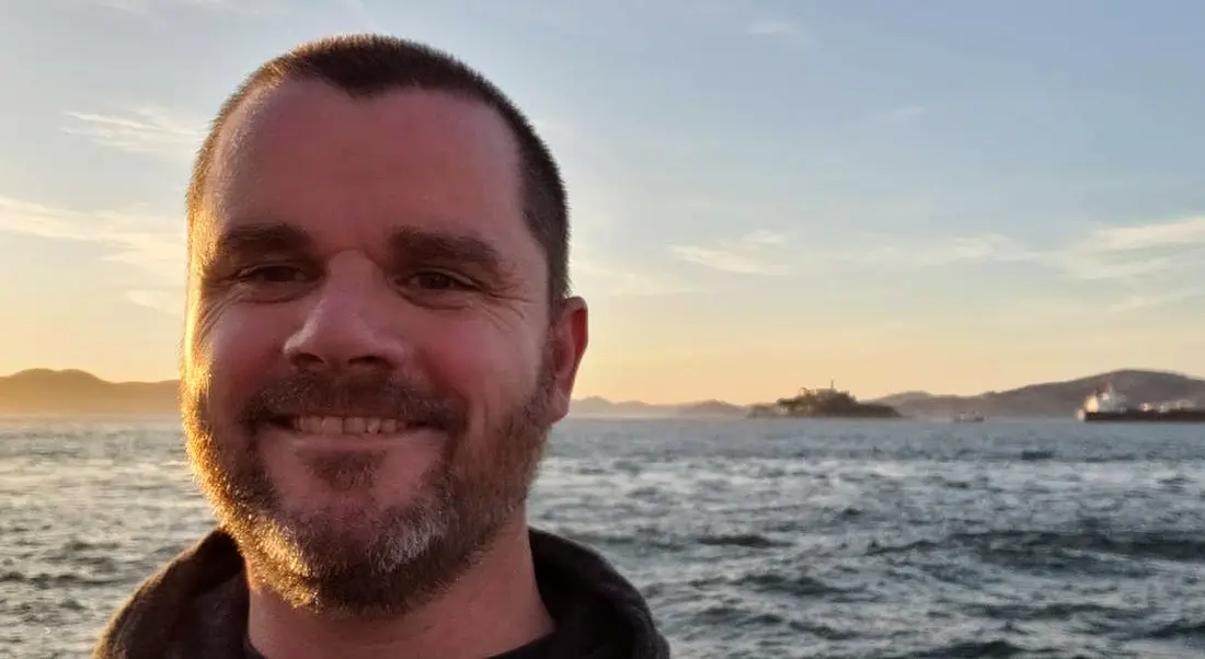 A close-up of Noel Crowley of Fidelity Investments smiling at the camera with the ocean in the background at sunset.