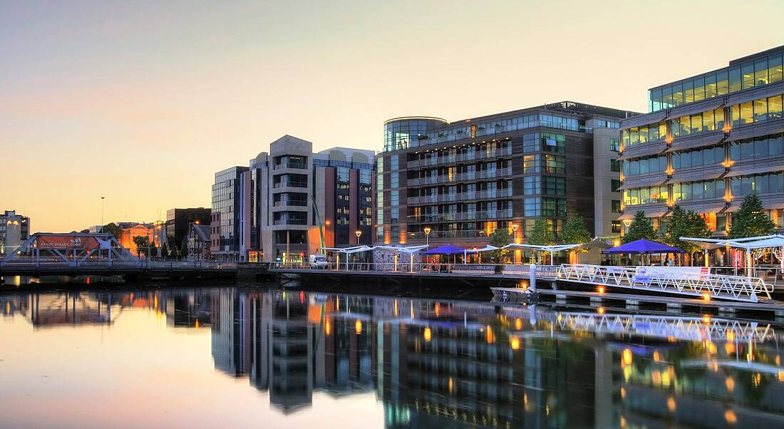 Buildings in Cork city lit up at dusk on the River Lee.