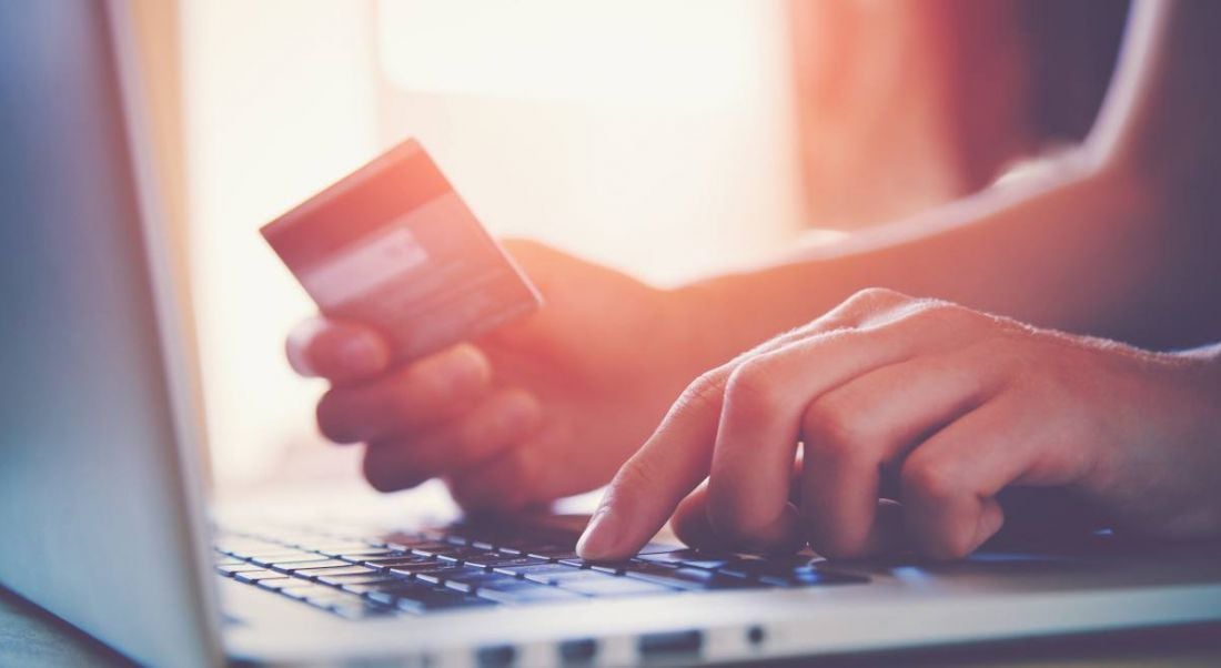 A person holding a credit card while typing on a laptop.