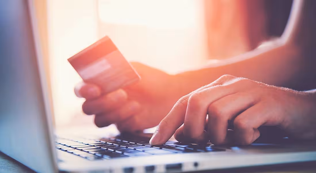 A person holding a credit card while typing on a laptop.
