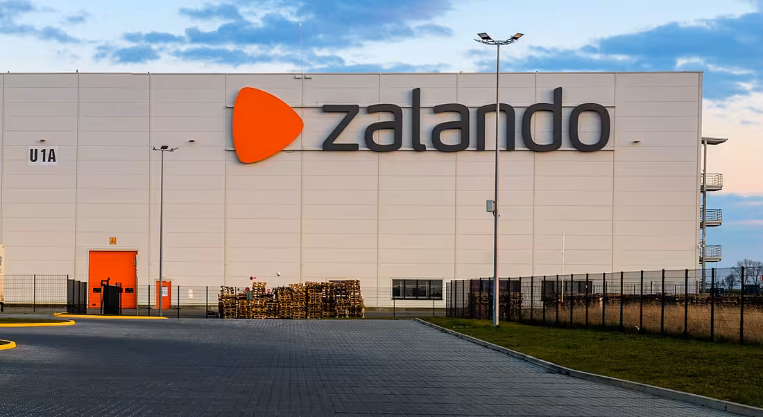 A large warehouse with the Zalando logo on the side against a blue sky at sunset.