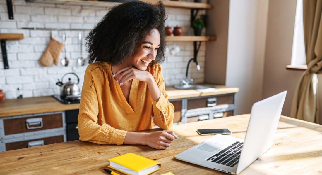 A woman remote working from her kitchen island in a brightly lit room.