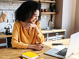 Cartoon of a woman working in cybersecurity with a large keyhole behind her and a laptop and desk in front of her.