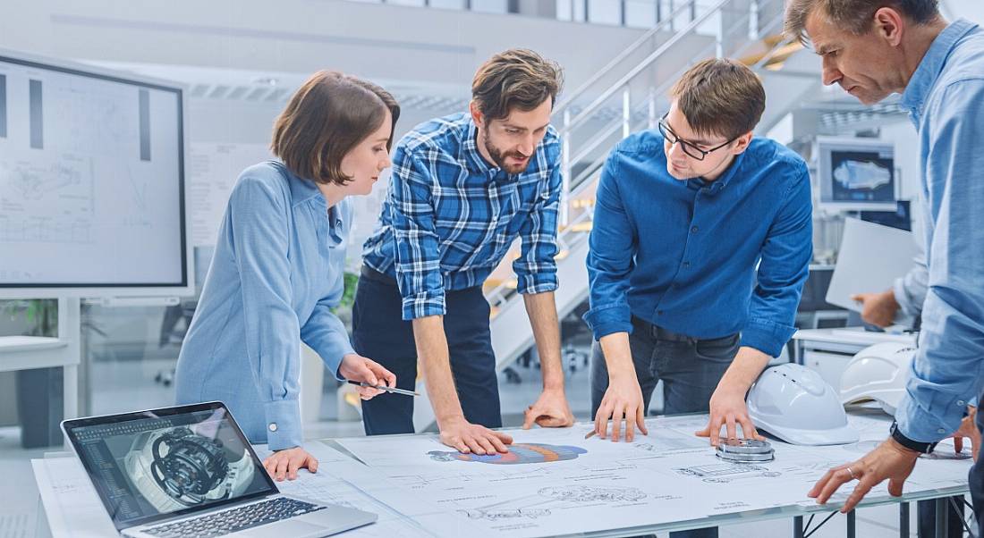 Four product designers gathered around a desk collaborating on a project.