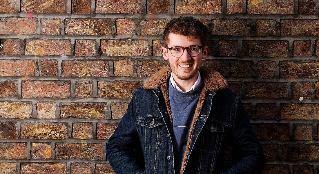 A headshot of Ben Butler, head of talent at Evervault, standing against a brick wall, smiling at the camera.