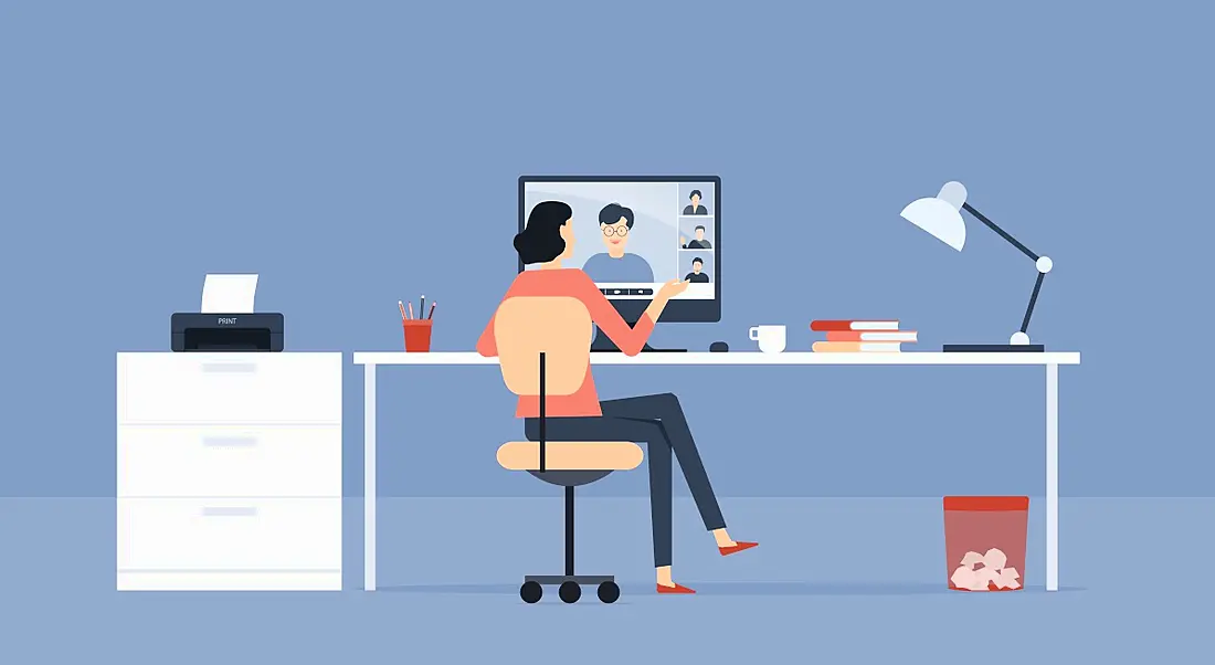 Cartoon graphic of a woman working at a desk as she talks to someone on the screen, symbolising hybrid working.