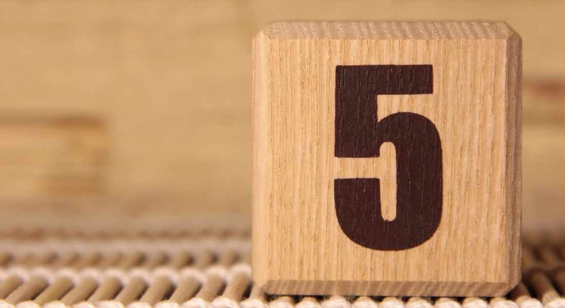 A wooden cube with the number five printed on it.