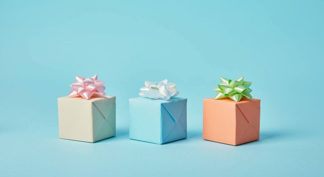 Three gift parcels with bows on top of them are sitting against a blue background.