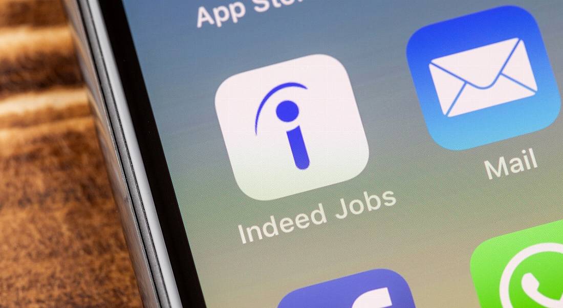 Smartphone displaying the Indeed Jobs app icon beside other apps, including email and WhatsApp.