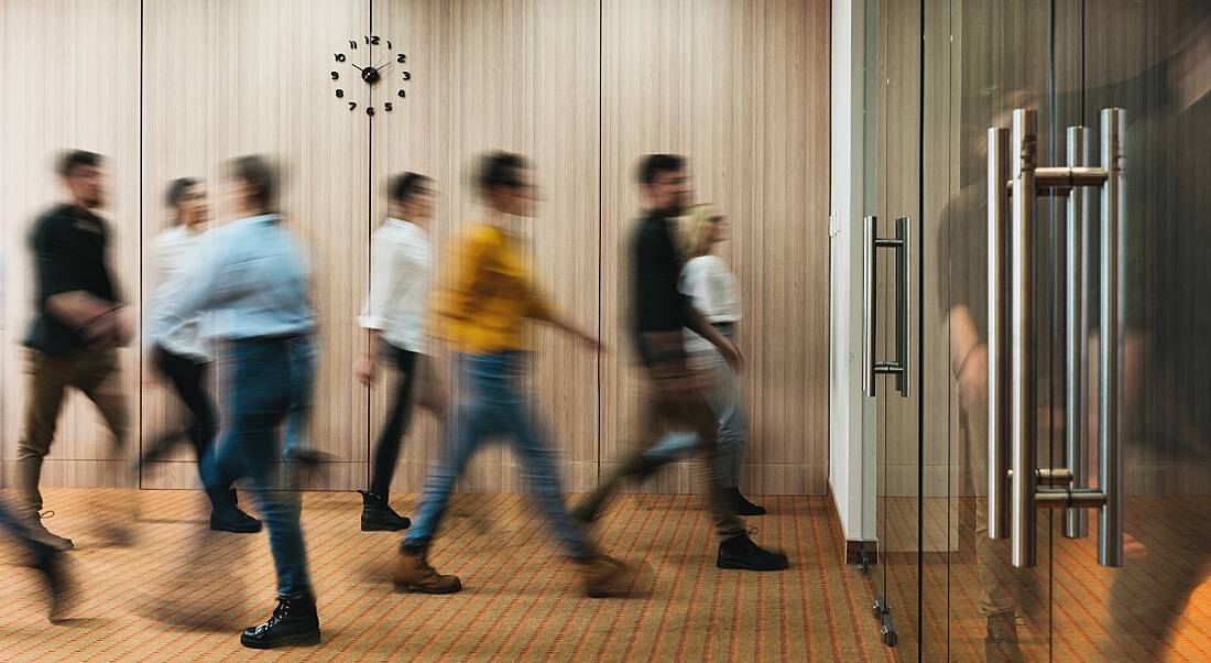 A motion-blue image of a group of people walking into an office.