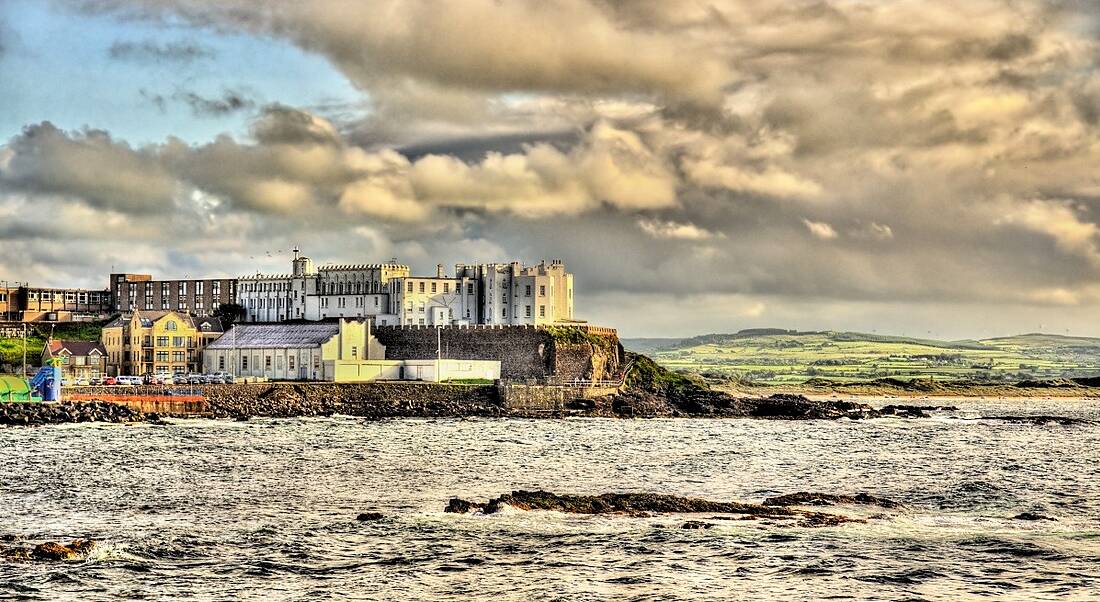 A view of the coast of Portstewart on a cloudy day. Buildings can be seen on a cliff overlooking the Atlantic Ocean.