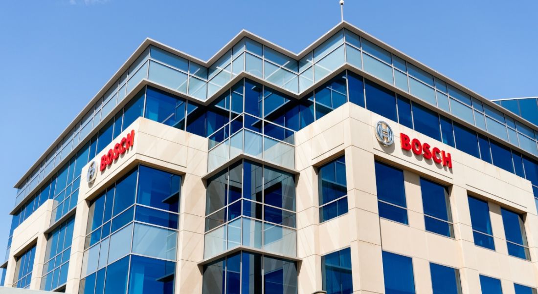 A large cream office building with many windows all around it against a blue sky with the Bosch logo on both sides of the building.