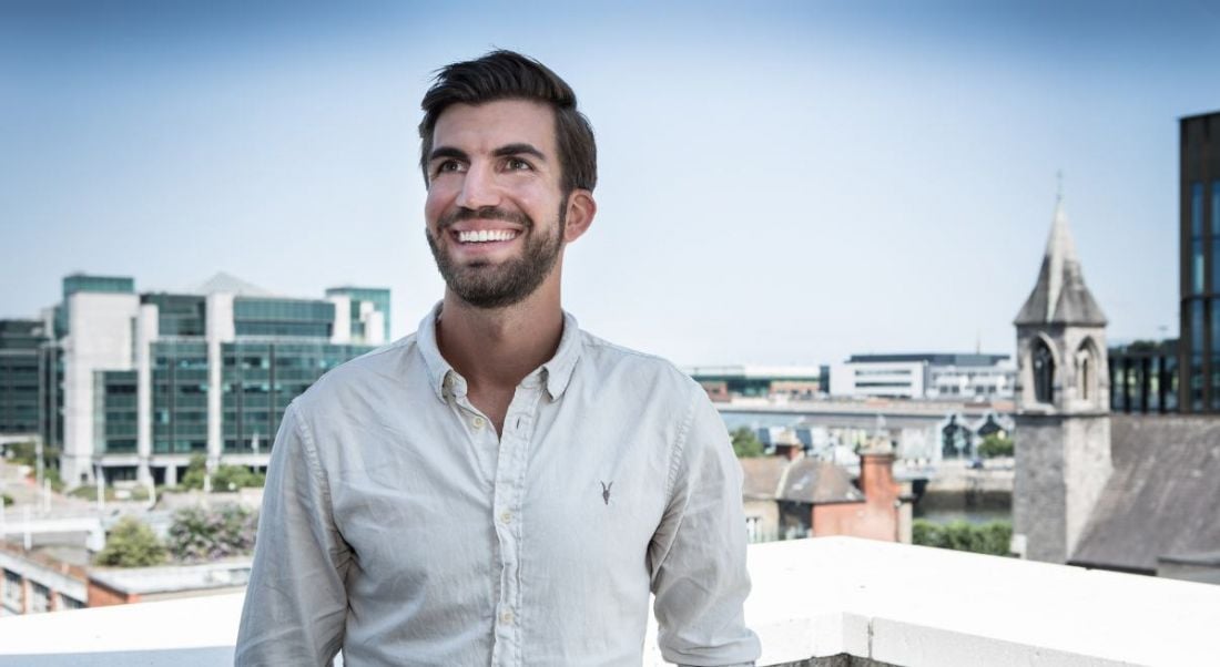 A man in a casual white shirt stands outside with a vast cityscape behind him in the background. He is Hanna Renner, CEO of Personio.