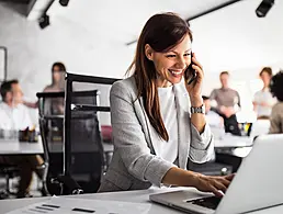 An animated image of a woman at a desk working at a laptop. Above her head, three people on screens with speech bubbles float, symbolising communication skills.