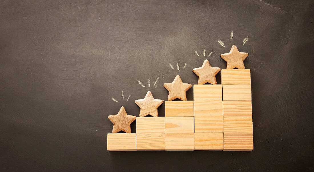 Wooden blocks stacked like a stepping system with wooden stars on top of each block like a ranking system.