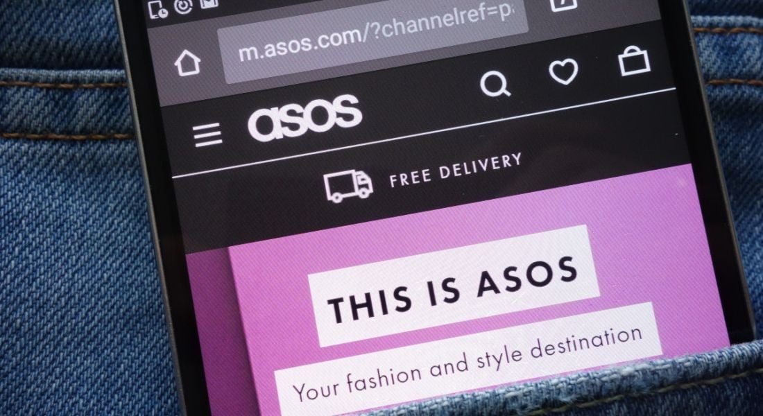 Smartphone displaying fashion retailer ASOS's webpage. The phone is in the pocket of a denim garment.