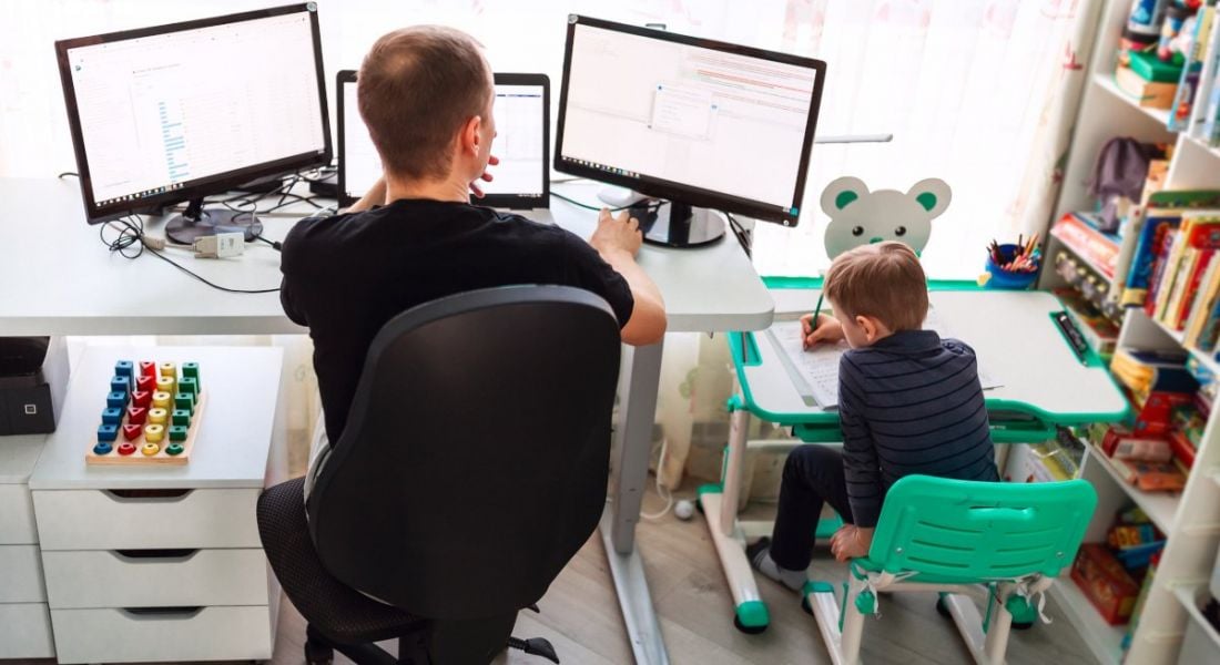 Man and child working at computers in a home office setting.