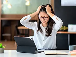 Woman doing thumbs up with one hand and thumbs down with the other as though evaluating a remote job. She is standing against a yellow background.