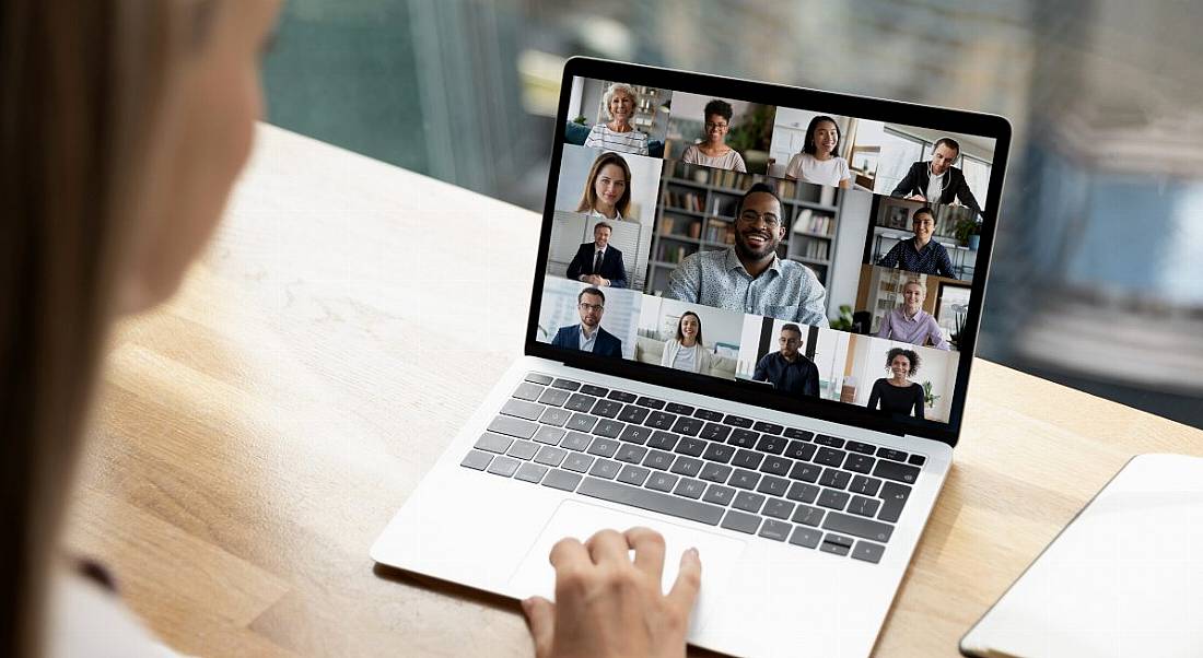 A woman is talking to colleagues using a video conferencing platform on her laptop.