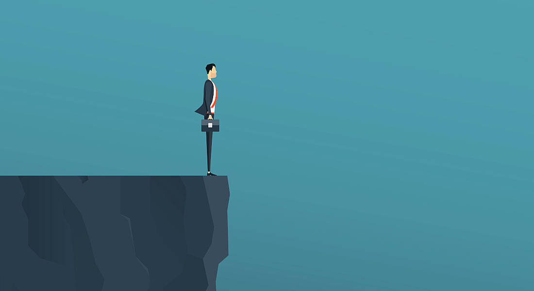 A graphic of a man in a suit holding a briefcase standing at the edge of a cliff against a dark blue background, symbolising a hiring cliff.