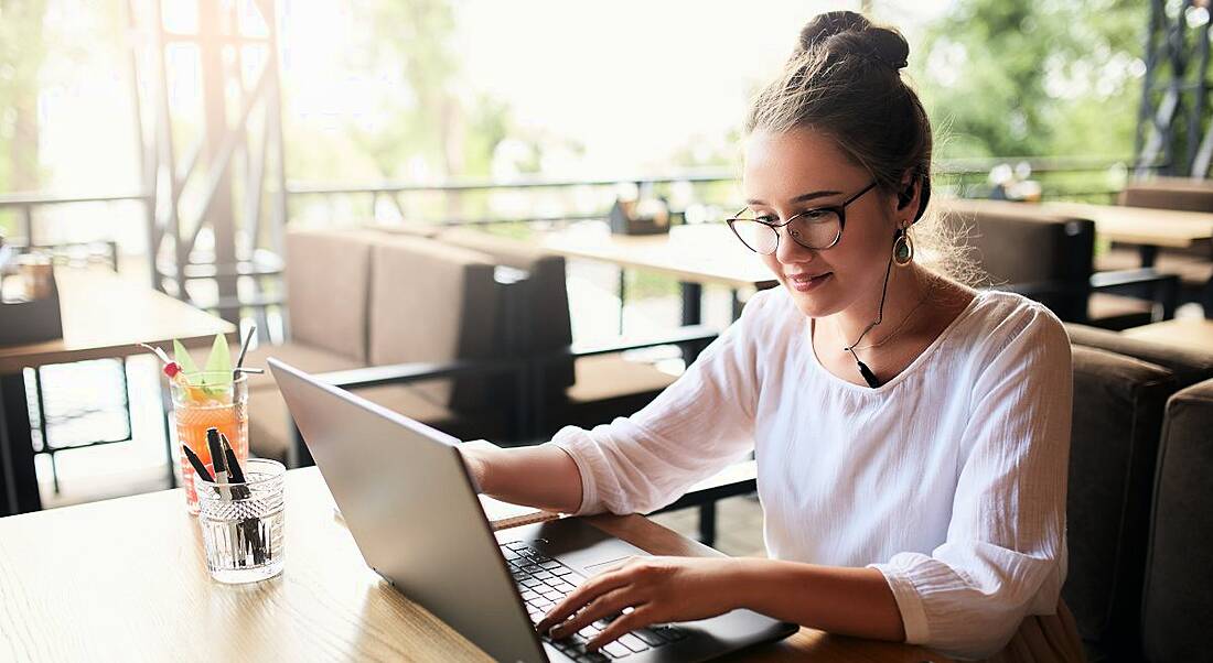 A woman working on laptop in a brightly lit room, symbolising managers communicating remotely.