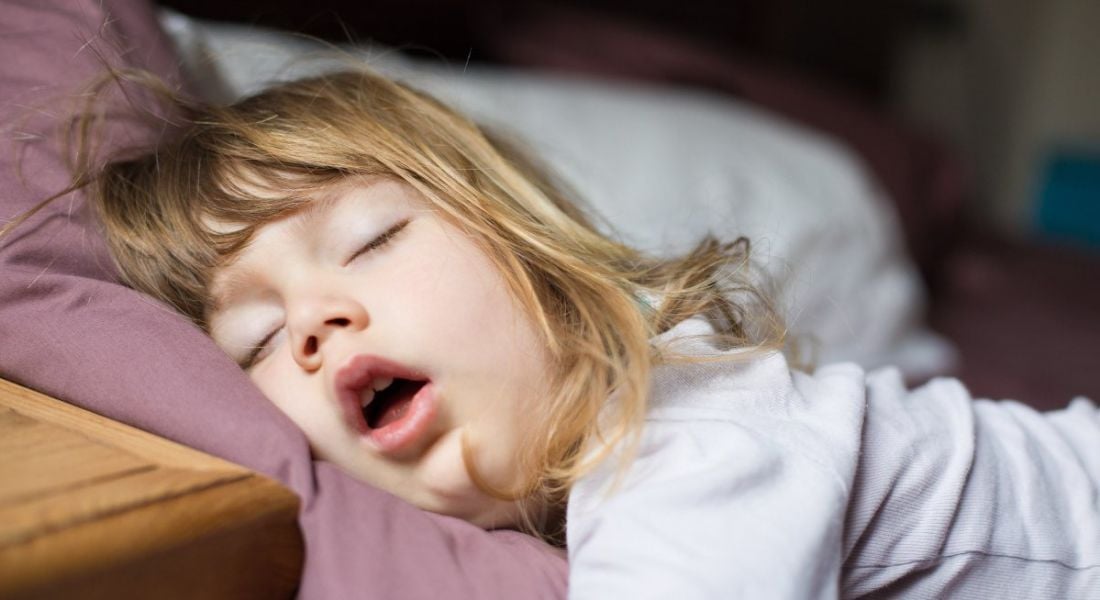 A young girl is sleeping with her mouth open.