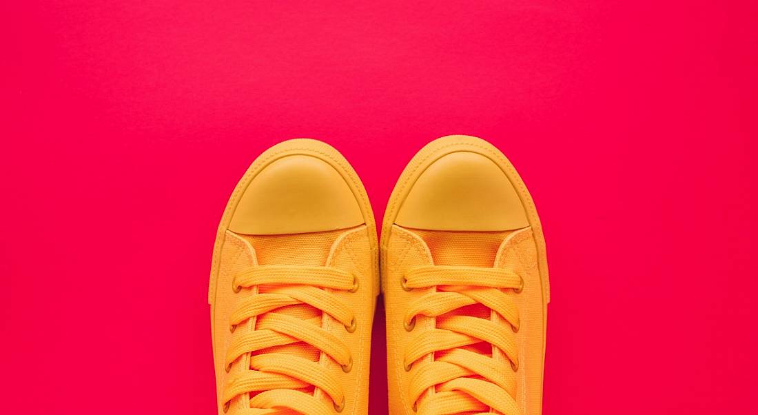 Bright yellow tennis shoes against a bright red background, symbolising taking your first step towards working in data.