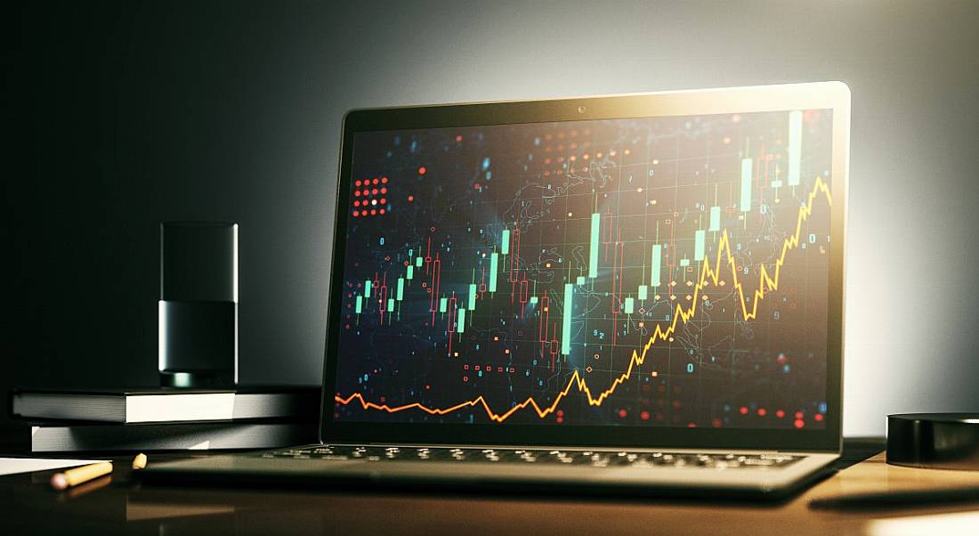 A laptop with colourful data on the screen is sitting on an office desk.