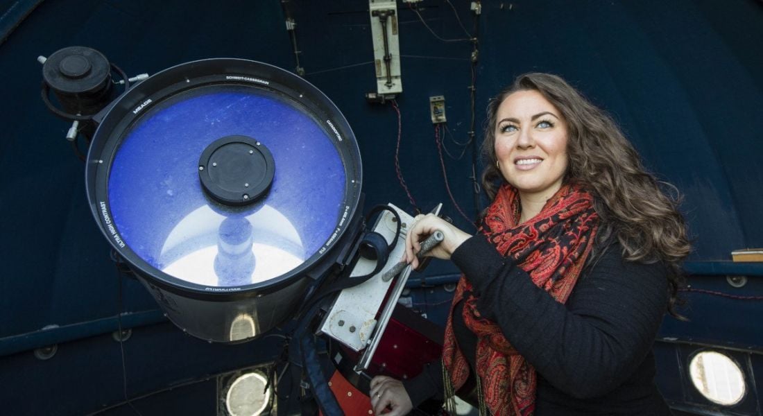 A woman operates a large telescope.