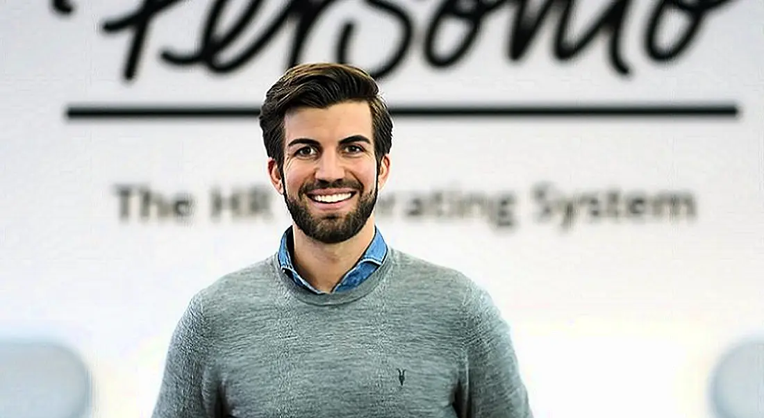 Chief executive of Personio Hanno Renner is standing in front of a wall that bears the company’s name.