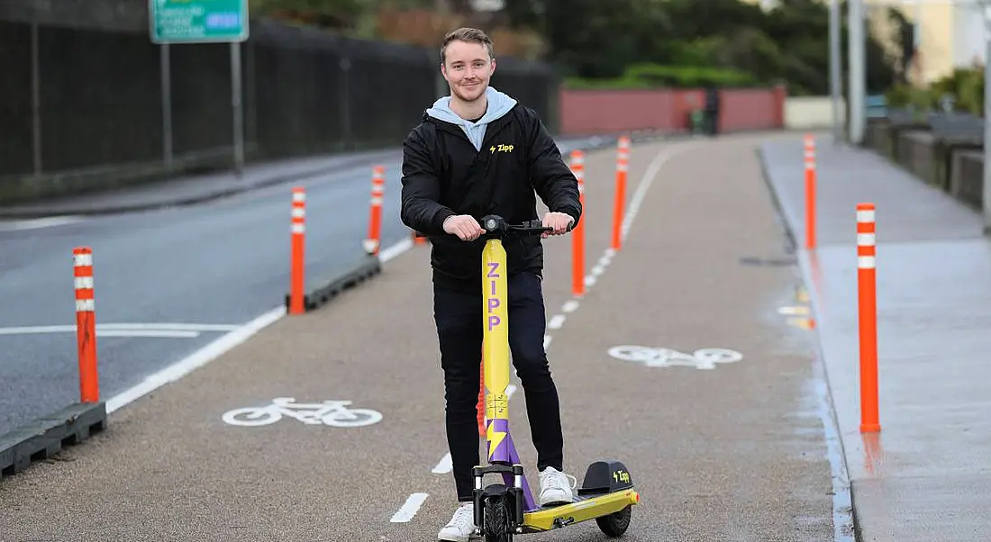 Charlie Gleeson stands by an e-scooter on a bike lane in Dublin.