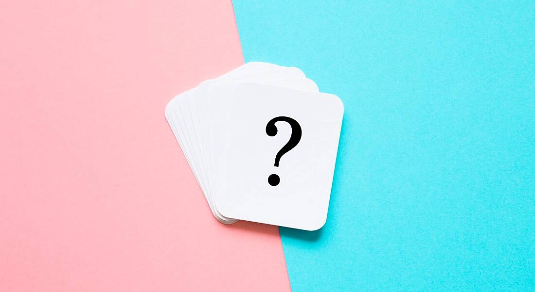 A stack of white playing cards are lying against a pink and blue background. The top card is showing a question mark.