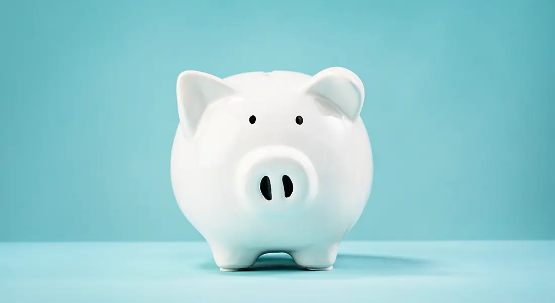 A white piggy bank sitting against a plain blue background.