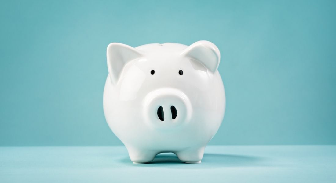 A white piggy bank sitting against a plain blue background.