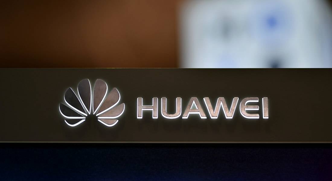 A backlit Huawei logo on a dark surface.