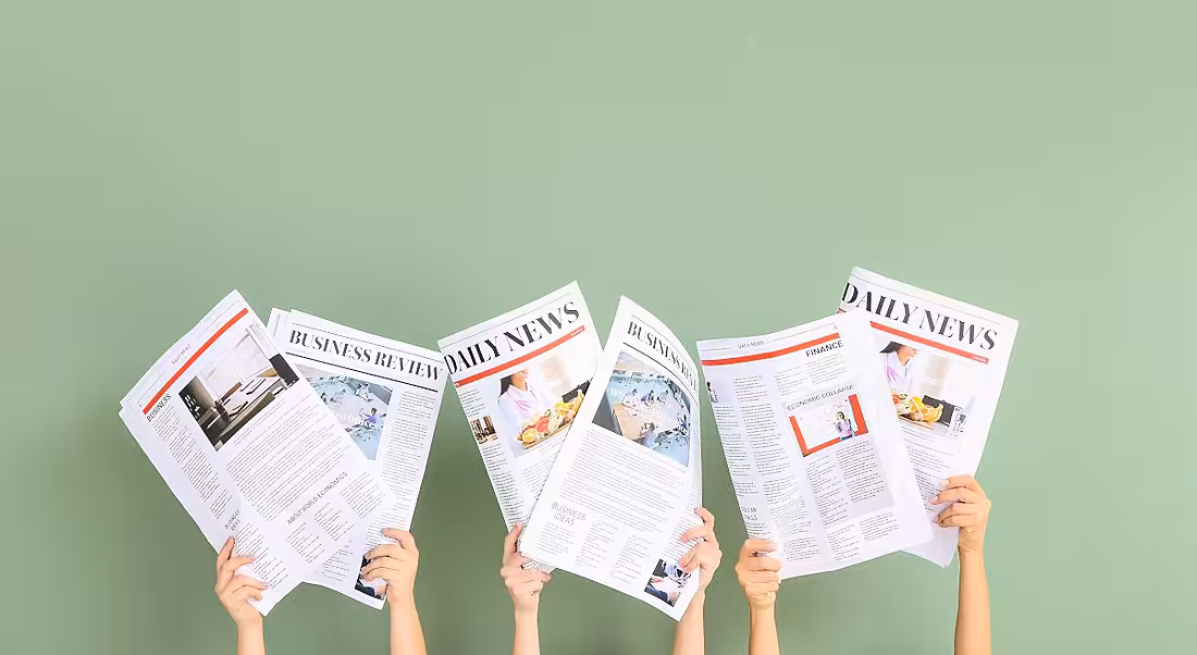 Three pairs of arms are holding up newspapers against a green background, symbolising jobs announcements.