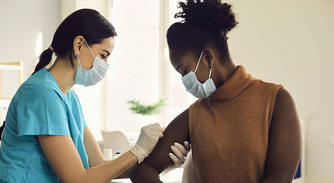 A medical professional is giving a patient a vaccination.