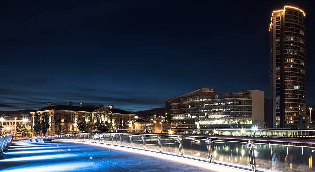 The Belfast cityscape seen from a bridge at night.