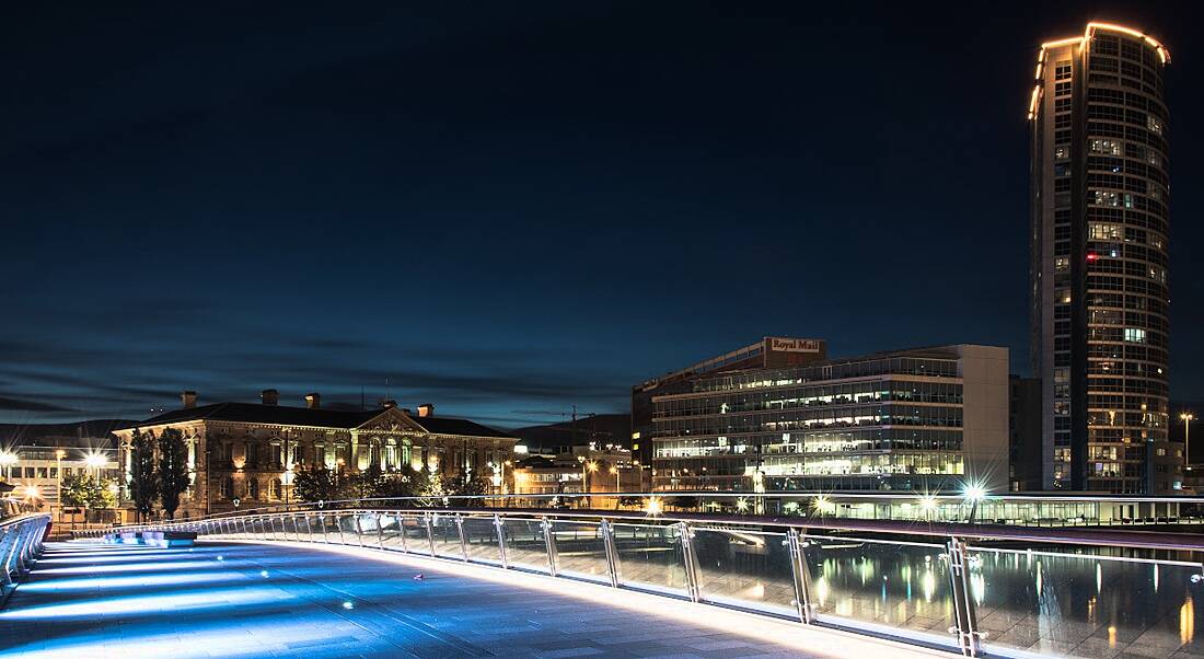 The Belfast cityscape seen from a bridge at night.