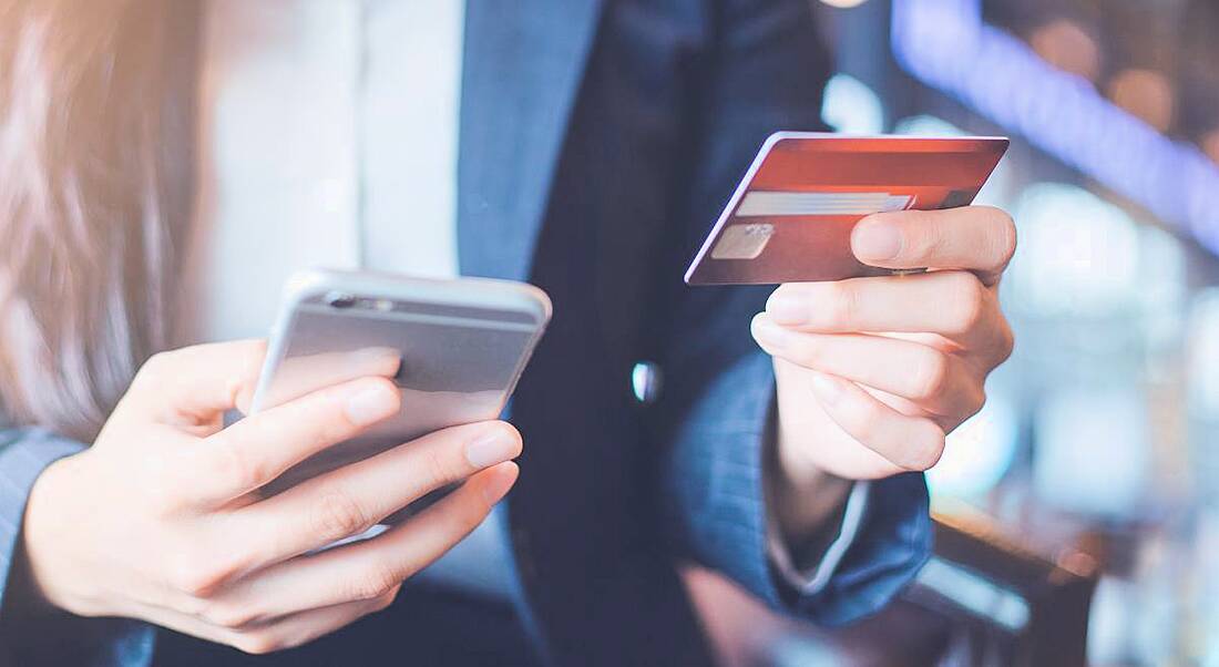 Close-up of a professional woman using a credit card to pay for something on her phone.