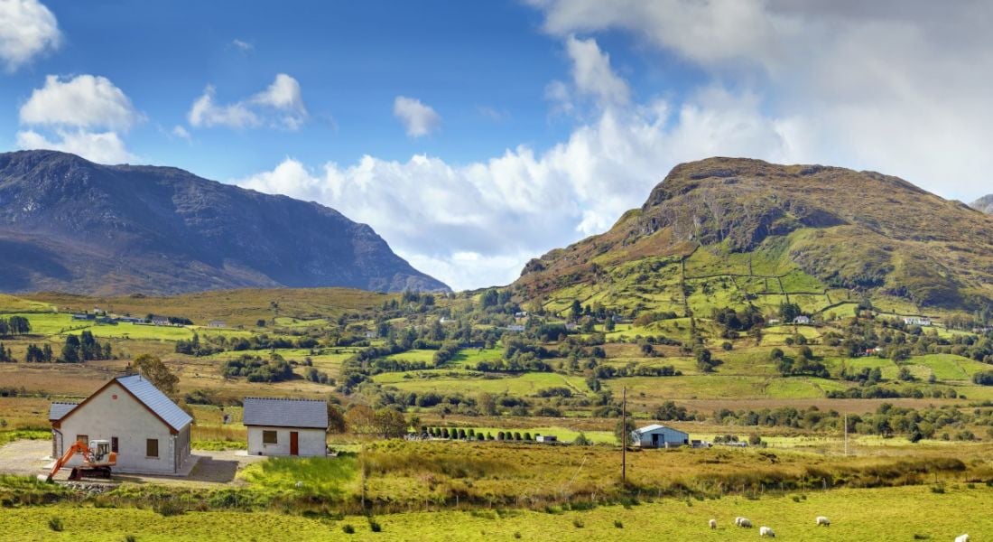 A panoramic photo of a mountainous region with a house in Galway, Ireland.