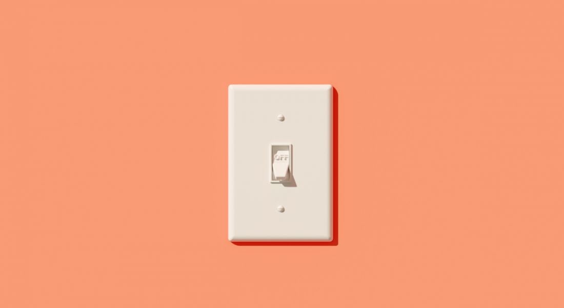 A white light switch on a peach-coloured wall.