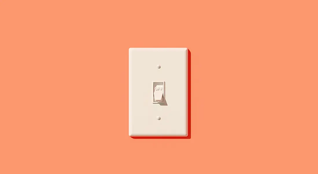 A white light switch on a peach-coloured wall.