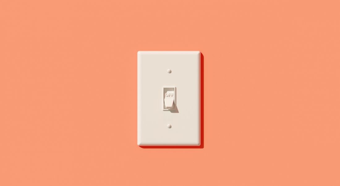 A white light switch on a peach-coloured wall.