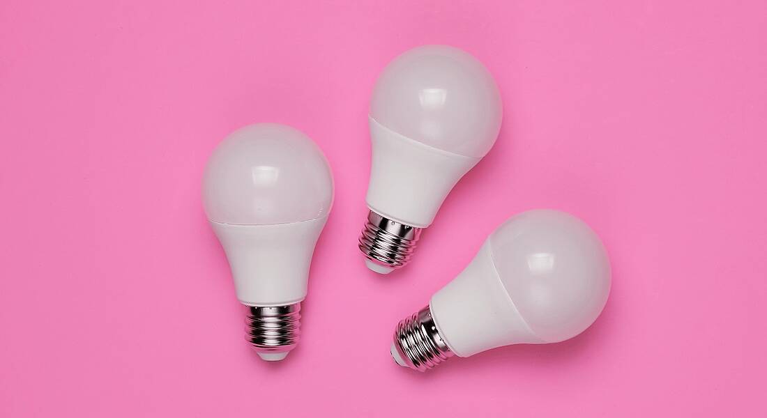 Three LED light bulbs on a bright pink background.