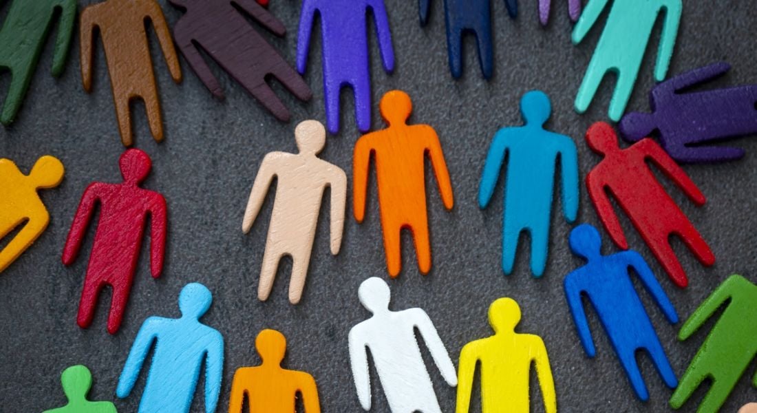 Plastic people figures in different colours laid out on a surface.