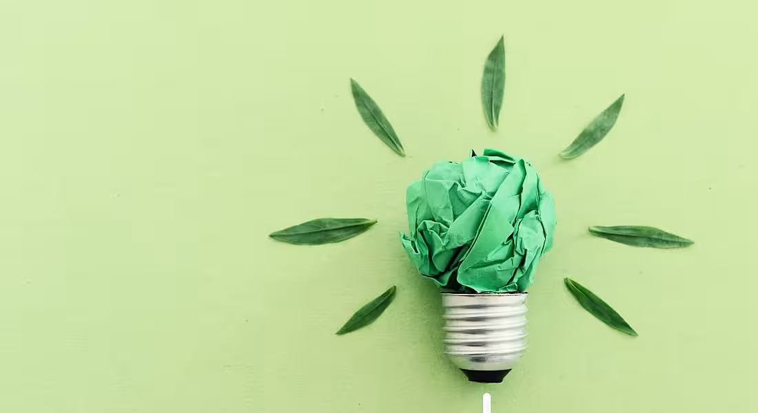 A light bulb made from green paper against a green background.