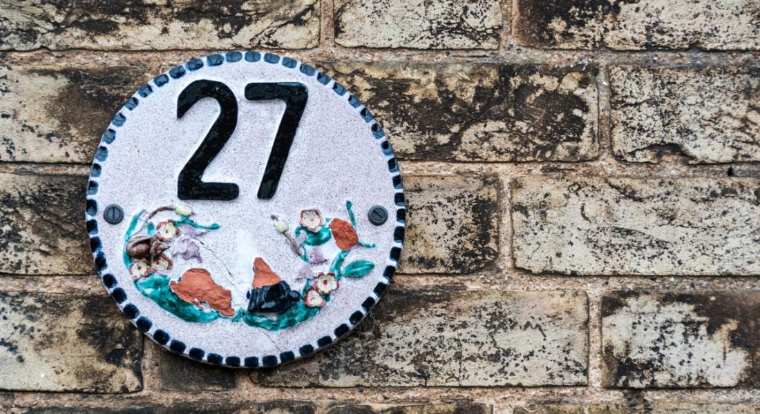 Decorative number 27 plate on a brick wall.