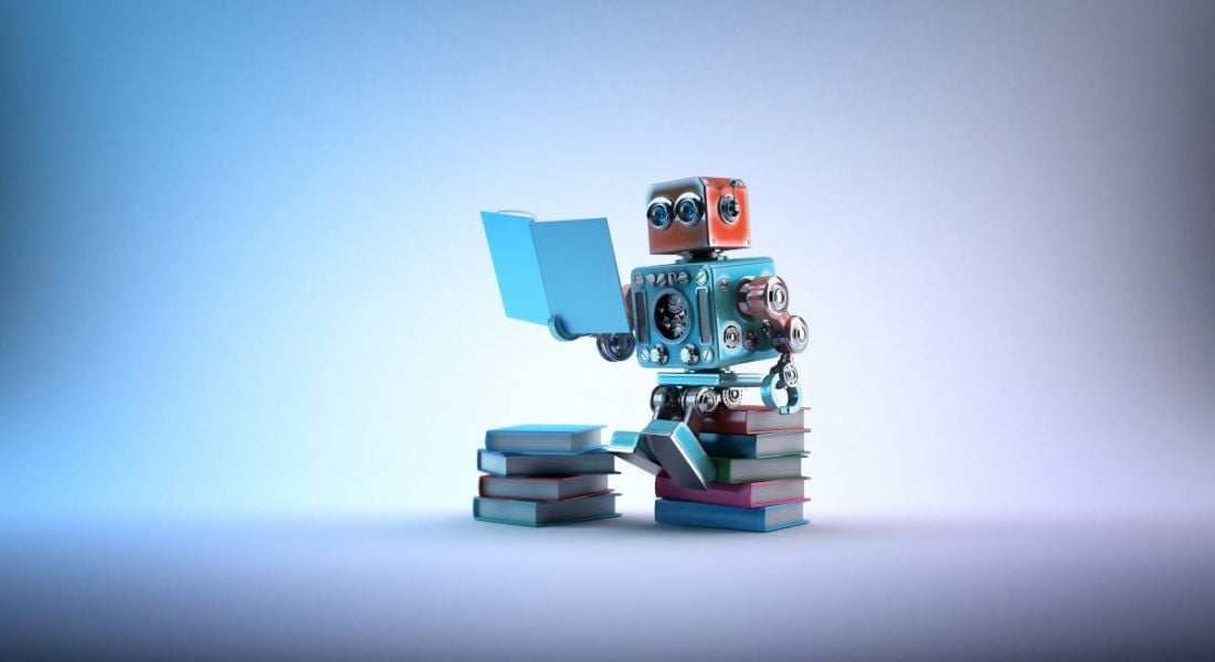 A cute toy robot is sitting on a stack of books and reading.