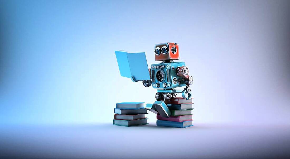 A cute toy robot is sitting on a stack of books and reading.